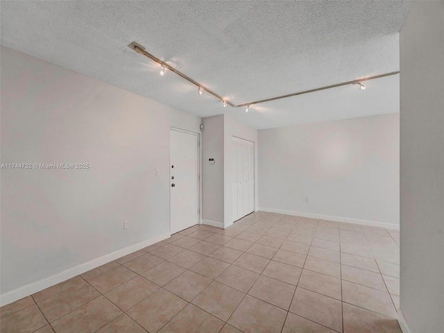 spare room featuring light tile patterned floors, track lighting, and a textured ceiling