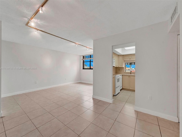 unfurnished room with sink, track lighting, a textured ceiling, and light tile patterned flooring