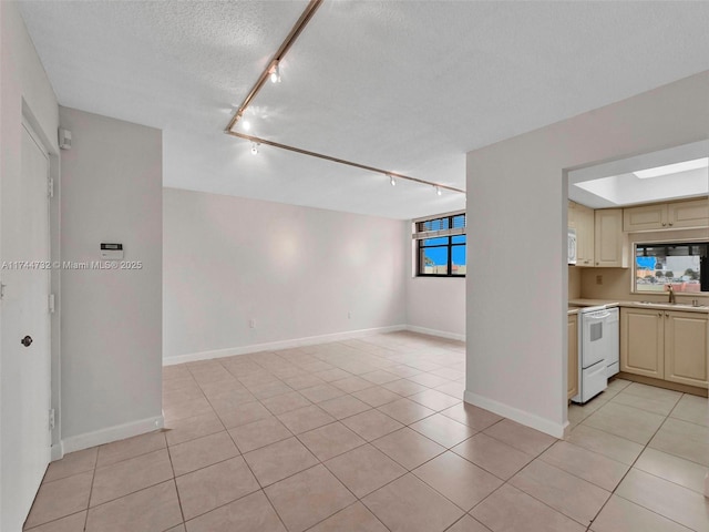 interior space featuring light tile patterned floors, white electric range, sink, cream cabinets, and a textured ceiling