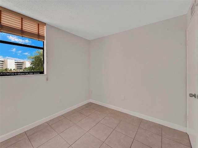 tiled spare room featuring a textured ceiling