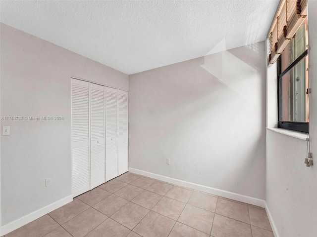 unfurnished bedroom featuring light tile patterned floors, a closet, and a textured ceiling