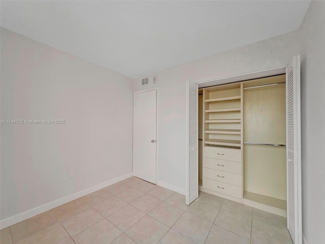 unfurnished bedroom with light tile patterned flooring and a closet