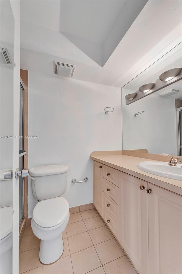 bathroom with tile patterned floors, toilet, a shower with door, and vanity