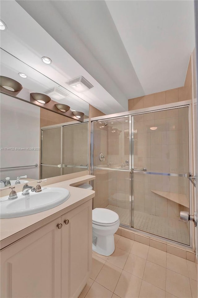 bathroom featuring vanity, toilet, a shower with door, and tile patterned flooring