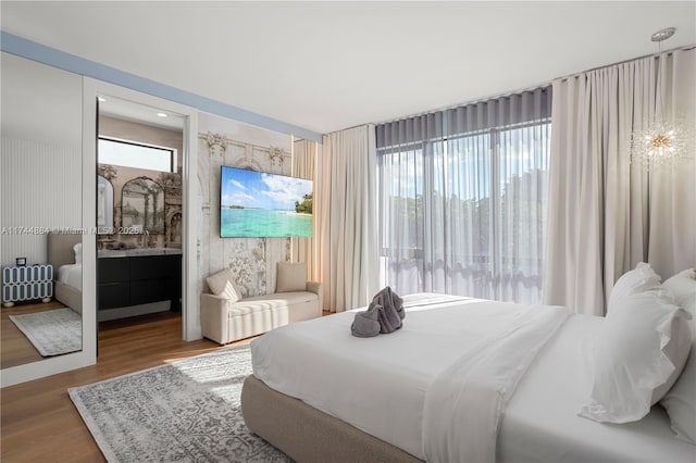 bedroom featuring radiator heating unit, light hardwood / wood-style floors, and ensuite bathroom