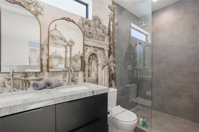 bathroom with a tile shower, vanity, and toilet