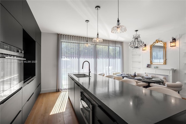 kitchen featuring oven, sink, hanging light fixtures, and a large island with sink