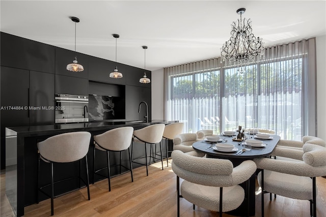 dining space featuring sink, a chandelier, and light hardwood / wood-style flooring