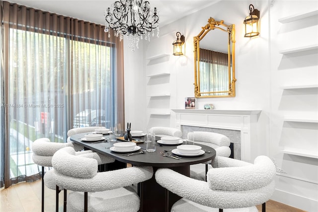 dining area featuring an inviting chandelier, built in shelves, light hardwood / wood-style flooring, and a wealth of natural light