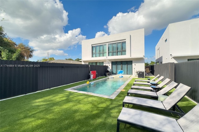 rear view of property featuring a yard, a fenced in pool, and a patio