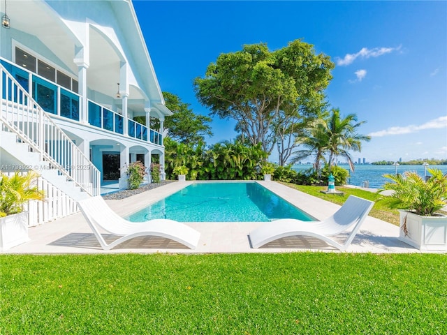 view of pool with a yard, a patio area, and a water view