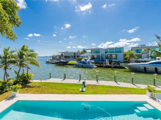 view of pool with a water view, a boat dock, and a lawn