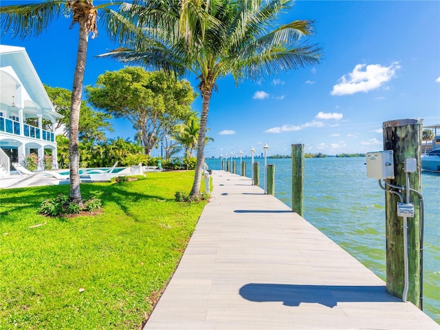 view of dock with a water view and a yard