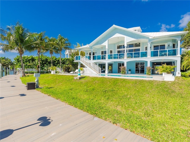 rear view of property with a yard, a patio, and a balcony