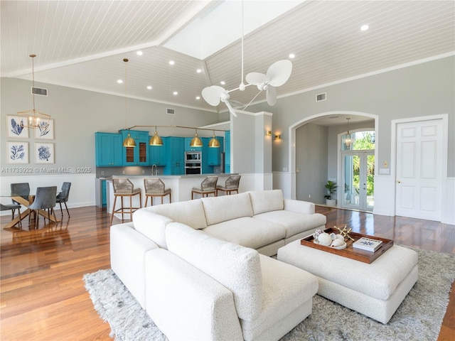 living room with french doors, ornamental molding, a chandelier, and light hardwood / wood-style flooring