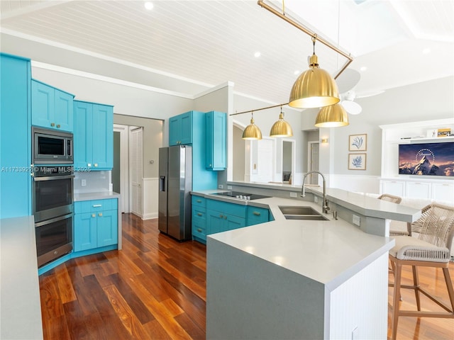 kitchen featuring appliances with stainless steel finishes, a breakfast bar, sink, and blue cabinets