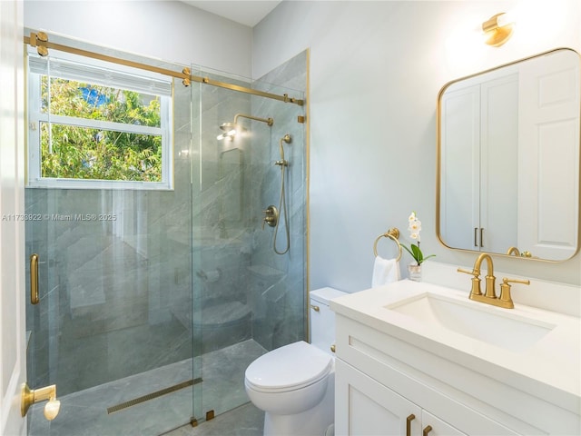 bathroom featuring vanity, a shower with door, and toilet