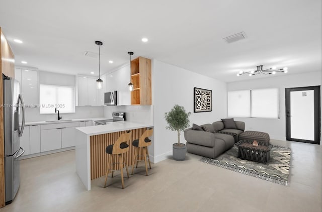 kitchen featuring stainless steel appliances, a peninsula, a sink, visible vents, and open floor plan