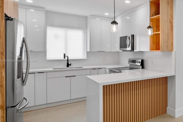 kitchen featuring appliances with stainless steel finishes, a sink, a peninsula, and modern cabinets