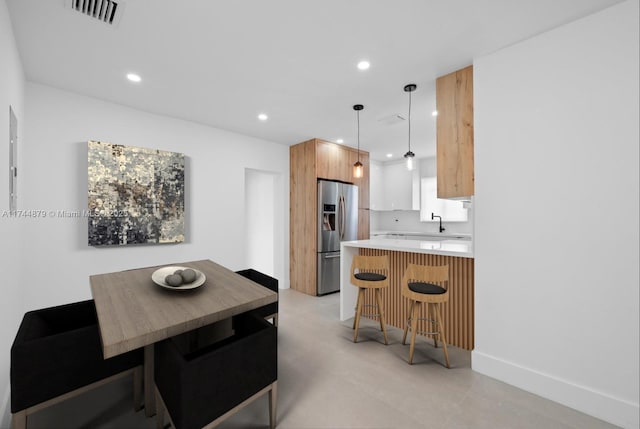 kitchen with recessed lighting, stainless steel fridge, visible vents, and a kitchen breakfast bar