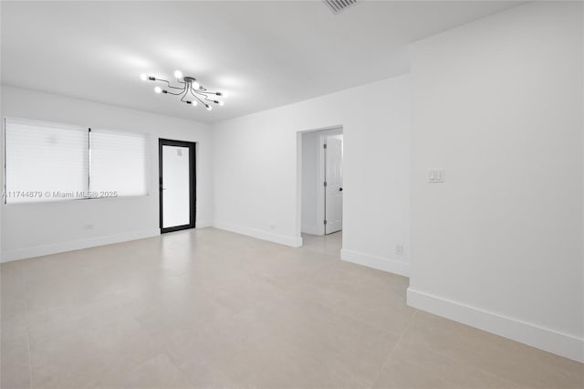 unfurnished room with baseboards and an inviting chandelier