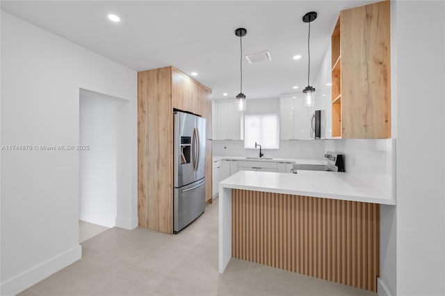 kitchen featuring a peninsula, range with electric stovetop, a sink, light countertops, and stainless steel refrigerator with ice dispenser