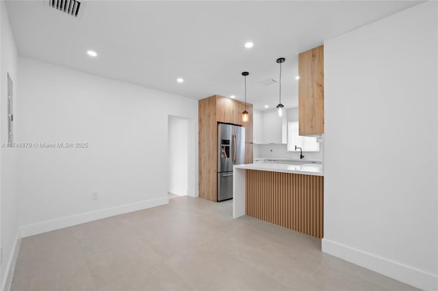 kitchen with stainless steel fridge, visible vents, a peninsula, light countertops, and recessed lighting