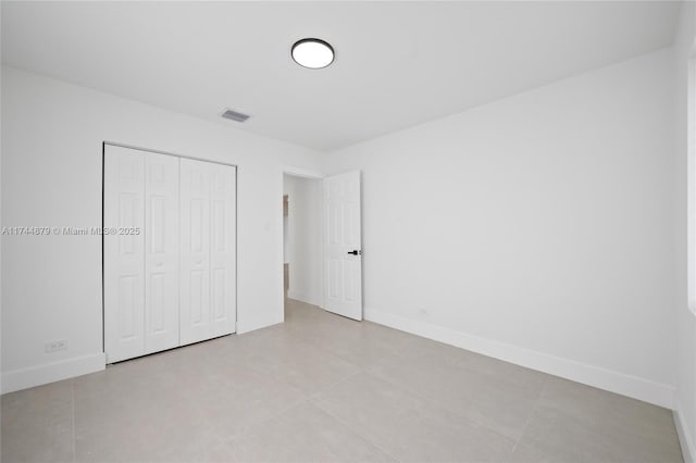 unfurnished bedroom with a closet, visible vents, and baseboards