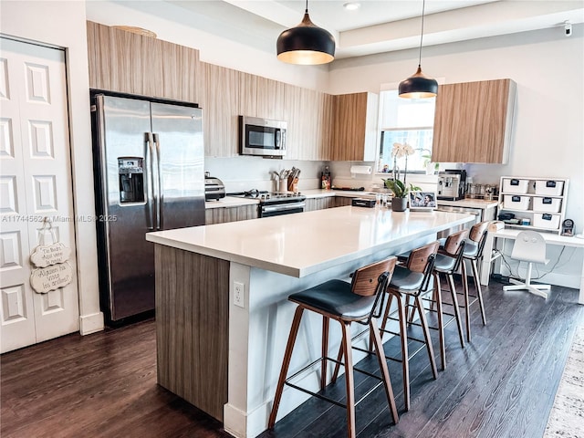 kitchen with pendant lighting, dark wood-type flooring, a center island, and appliances with stainless steel finishes