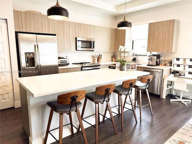 kitchen with hanging light fixtures, a kitchen breakfast bar, stainless steel appliances, and a center island