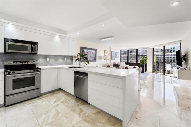 kitchen with stainless steel appliances, a peninsula, a sink, backsplash, and modern cabinets
