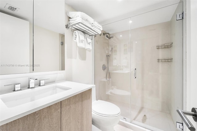 bathroom with vanity, a shower with shower door, and toilet