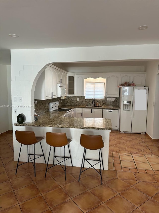 541 NE 199th Ln Unit 2X, Miami, FL 33179 - kitchen featuring a sink, decorative backsplash, a breakfast bar, white appliances, and a peninsula