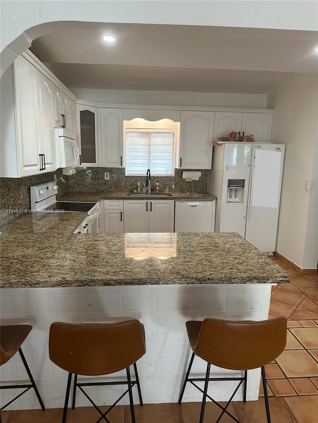 541 NE 199th Ln Unit 2X, Miami, FL 33179 - kitchen with a sink, white appliances, glass insert cabinets, a kitchen bar, and a peninsula