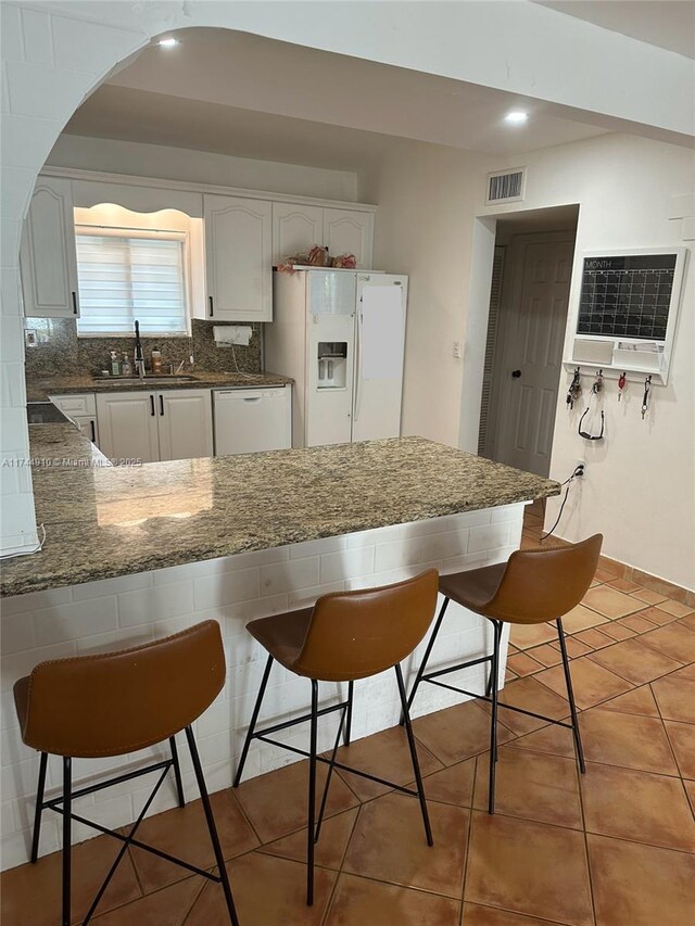 541 NE 199th Ln Unit 2X, Miami, FL 33179 - kitchen featuring a peninsula, a kitchen breakfast bar, a sink, visible vents, and white appliances