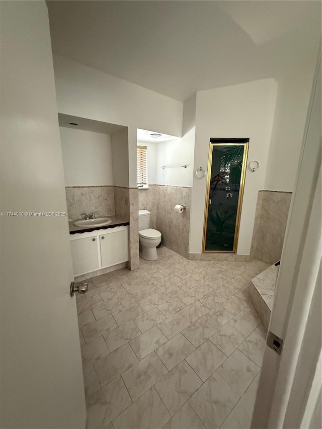 541 NE 199th Ln Unit 2X, Miami, FL 33179 - bathroom with a wainscoted wall, toilet, tile walls, marble finish floor, and vanity