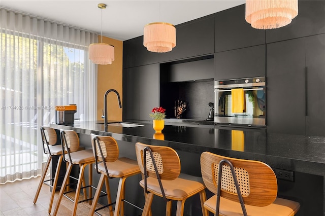 kitchen with pendant lighting, a kitchen breakfast bar, oven, and sink