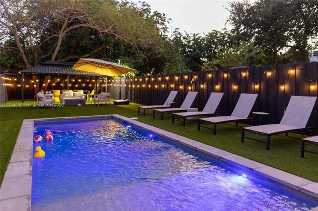 view of pool with outdoor lounge area and a lawn