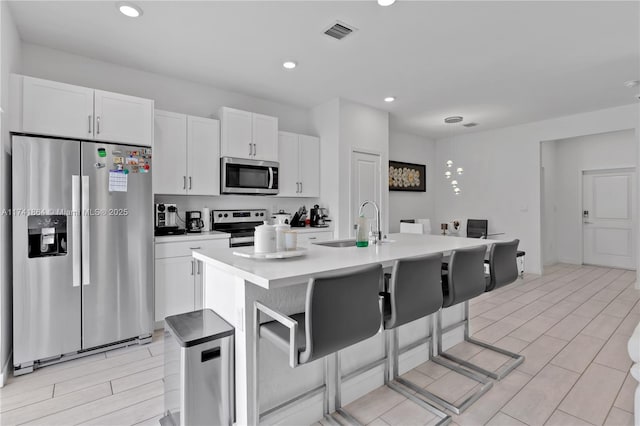 kitchen featuring an island with sink, white cabinetry, sink, a breakfast bar area, and stainless steel appliances