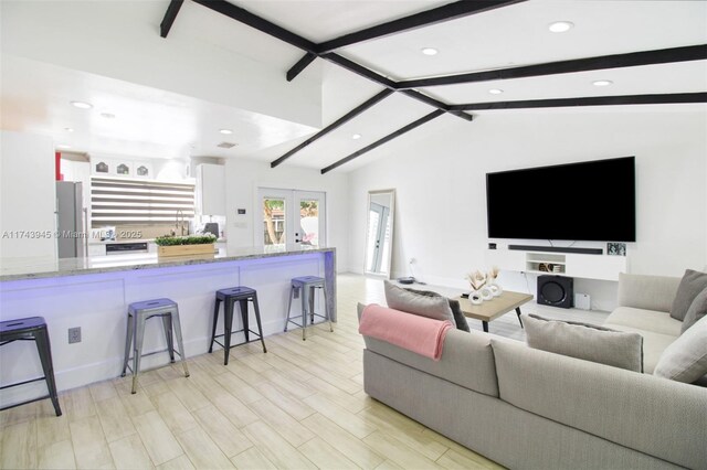 living room with french doors, light hardwood / wood-style floors, and vaulted ceiling with beams