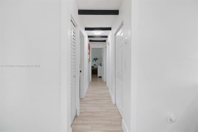 hall featuring beam ceiling and light hardwood / wood-style flooring