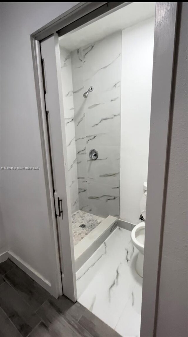 bathroom with toilet and a tile shower