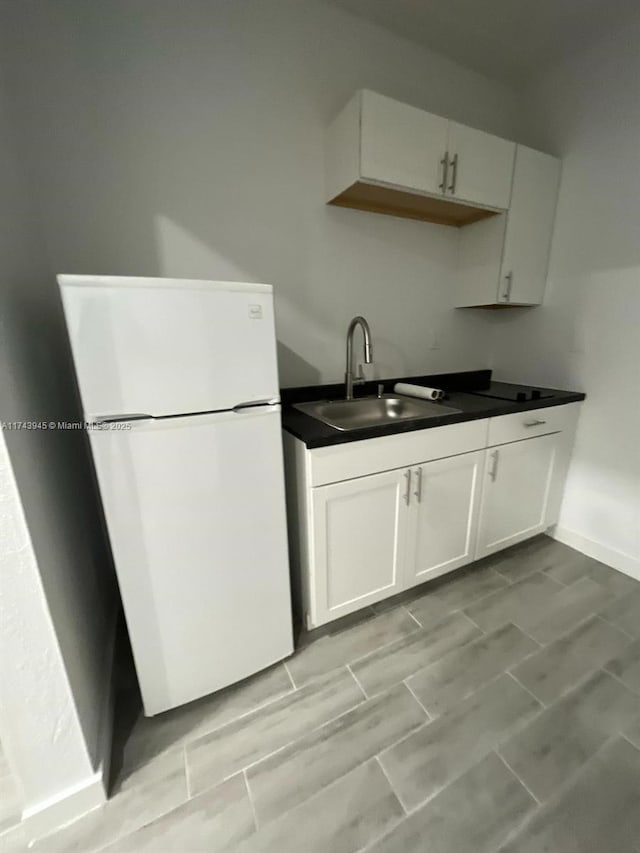 kitchen featuring white refrigerator, white cabinetry, and sink