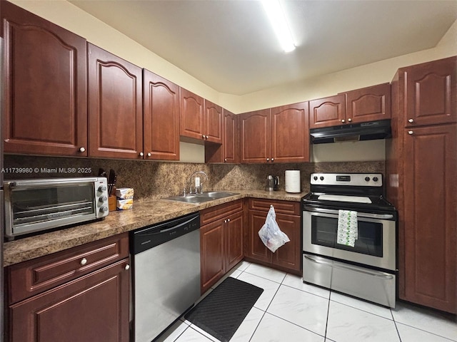 kitchen with a toaster, tasteful backsplash, appliances with stainless steel finishes, a sink, and under cabinet range hood