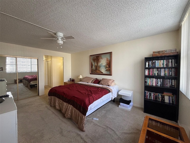 bedroom featuring multiple closets, ceiling fan, light carpet, and a textured ceiling