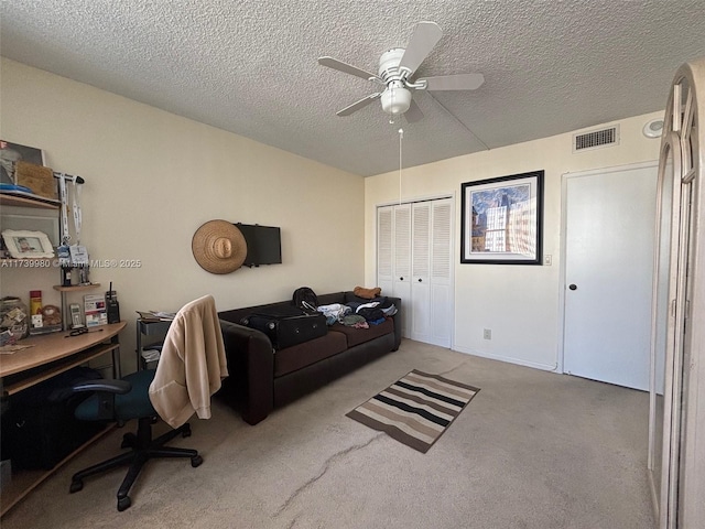 carpeted office space with ceiling fan and a textured ceiling