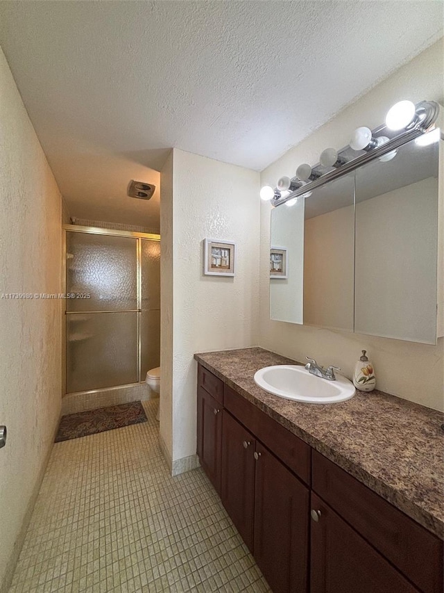 bathroom featuring walk in shower, vanity, a textured ceiling, and toilet