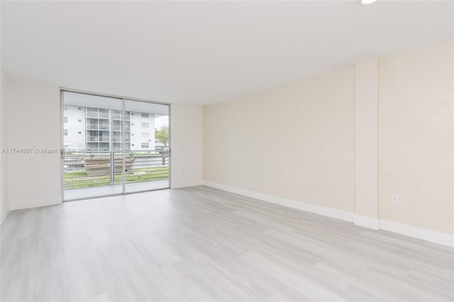 empty room with floor to ceiling windows and light wood-type flooring