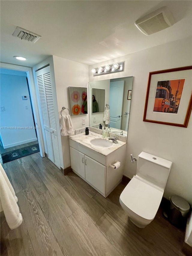 bathroom with hardwood / wood-style flooring, vanity, and toilet