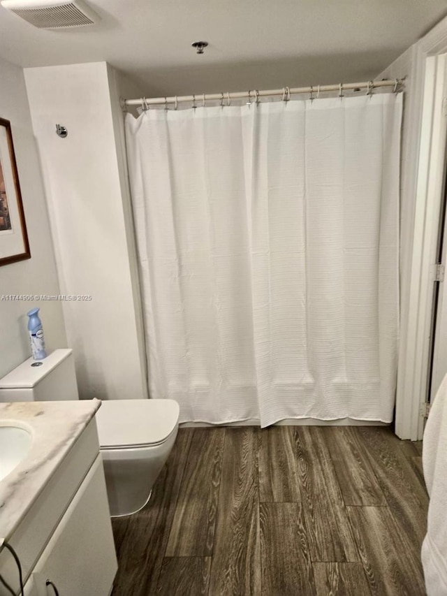 bathroom featuring wood-type flooring, toilet, and vanity